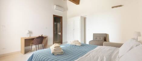 A bedroom with a bed, a desk, a chair, a wardrobe, and an air conditioning unit.