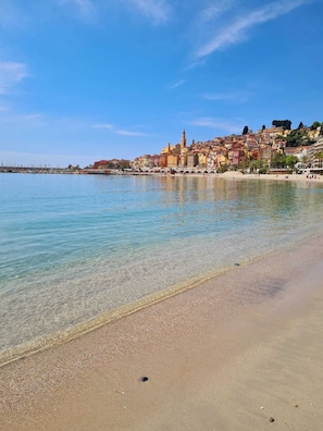 A coastal town with a clear beach, a marina, and colorful buildings.