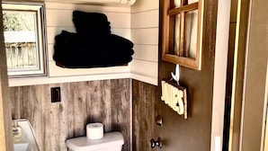 A compact bathroom with a toilet, a small sink, and a window.