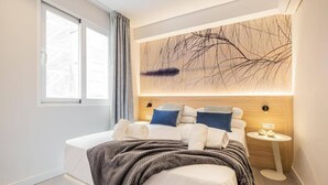Een moderne slaapkamer met een groot bed, een nachtkastje en een wandlamp.