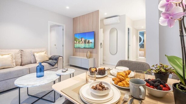 Een moderne woonkamer met een bank, een bijzettafeltje en een eethoek met ontbijtartikelen.