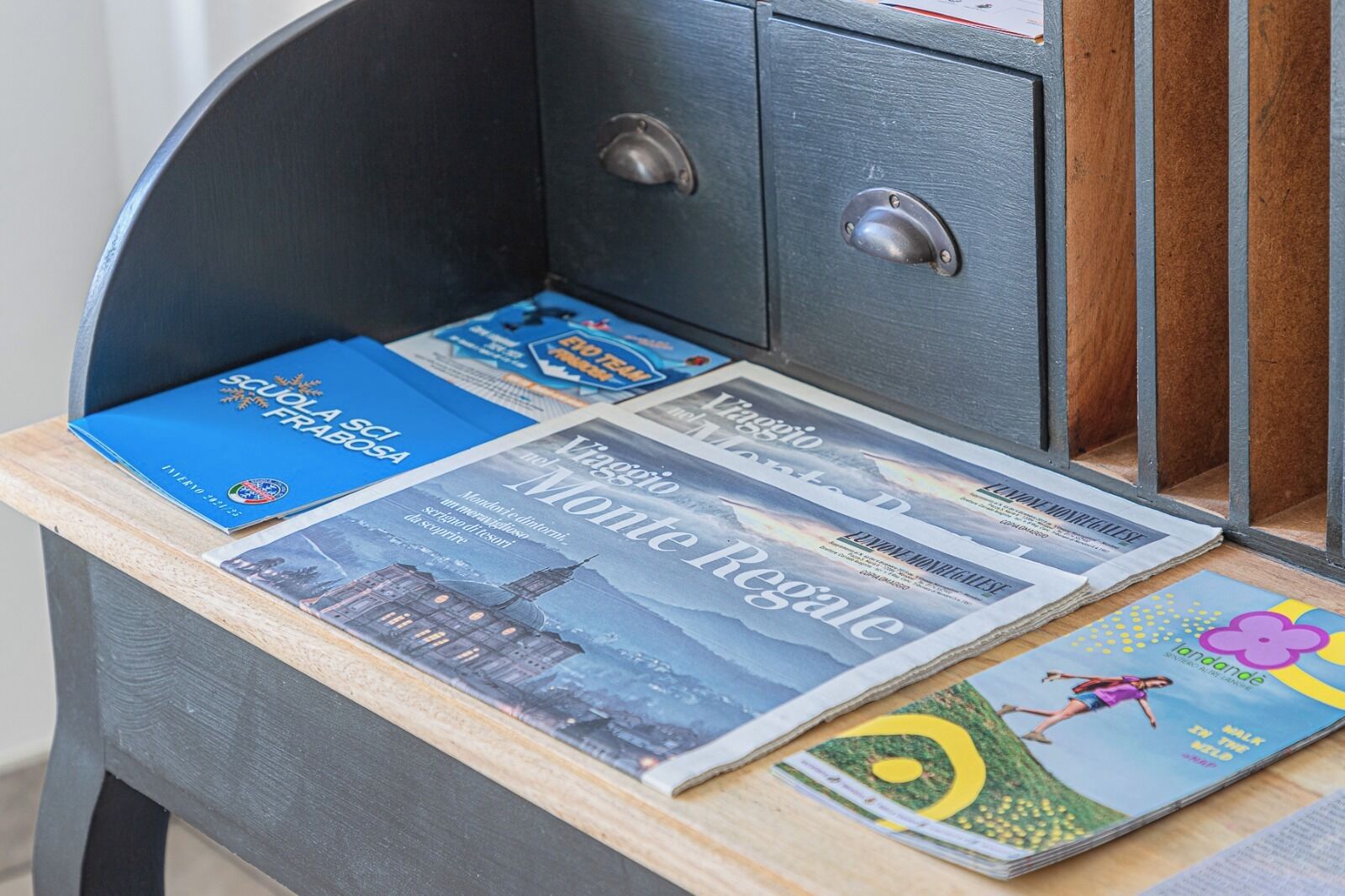 A desk with a stack of travel brochures and a magazine.