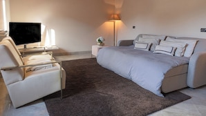 Een moderne slaapkamer met een bed, een stoel, een televisie en een lamp.