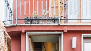 Een gebouw ingang met een trap naar een hoger gelegen deel, een deurmat en twee plantenpotten.