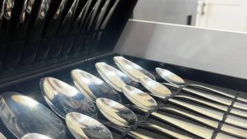 Una cocina con encimera negra y un estante con varios utensilios.