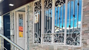Una escalera de piedra con barandillas de metal que conduce a una puerta con detalles de hierro forjado.