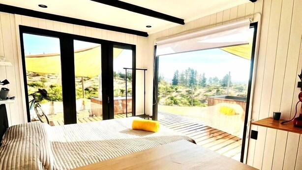 Un coin repas moderne avec une table en bois, deux bougies et un coussin jaune.