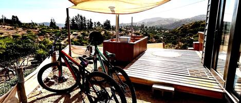 Ein Balkon mit Holzboden, einem Fahrrad und einem großen Sonnensegel.