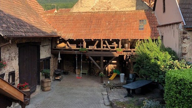 A courtyard with a pyramid-shaped structure, a wooden deck, and a stone wall. - Charming gîte, former wine estate, sleeps 13 (Orschwihr)