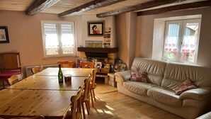 A cozy living room with a wooden dining table, leather sofa, and a fireplace. - Charming gîte, former wine estate, sleeps 13 (Orschwihr)