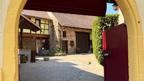 A cobblestone courtyard with a yellow archway leading to a building with a red door. - Charming gîte, former wine estate, sleeps 13 (Orschwihr)