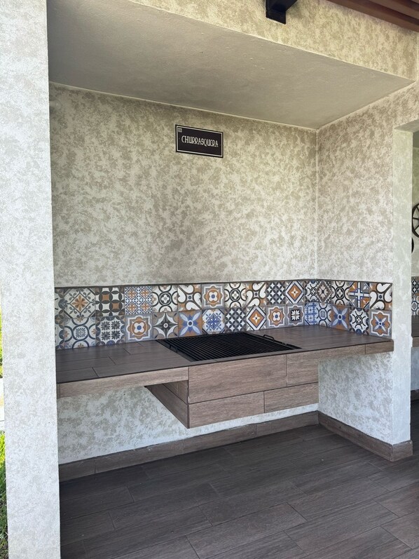 A kitchen with a tiled backsplash, a built-in grill, and a sign that reads "CHURRASQUEIRA." - Charming 3-bedroom colonial house with WiFi, fitness room in lovely Ciudad Vieja (Ciudad Vieja)