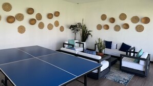 Ein Wohnzimmer mit Tischtennisplatte, einer Sofagarnitur und dekorativen Wandgestaltungen.