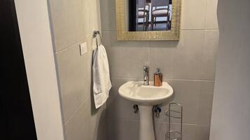 Een badkamer met een witte wastafel, een spiegel met gouden lijst en een handdoek aan een rek.