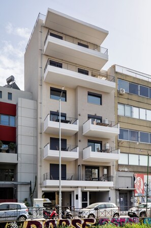 Ein mehrgeschossiges Gebäude mit Balkonen, einem Parkplatz und Graffiti an der unteren Fassade.