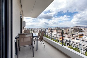 Ein Balkon mit Tisch und Stühlen mit Blick auf eine Skyline und mehrere Gebäude.