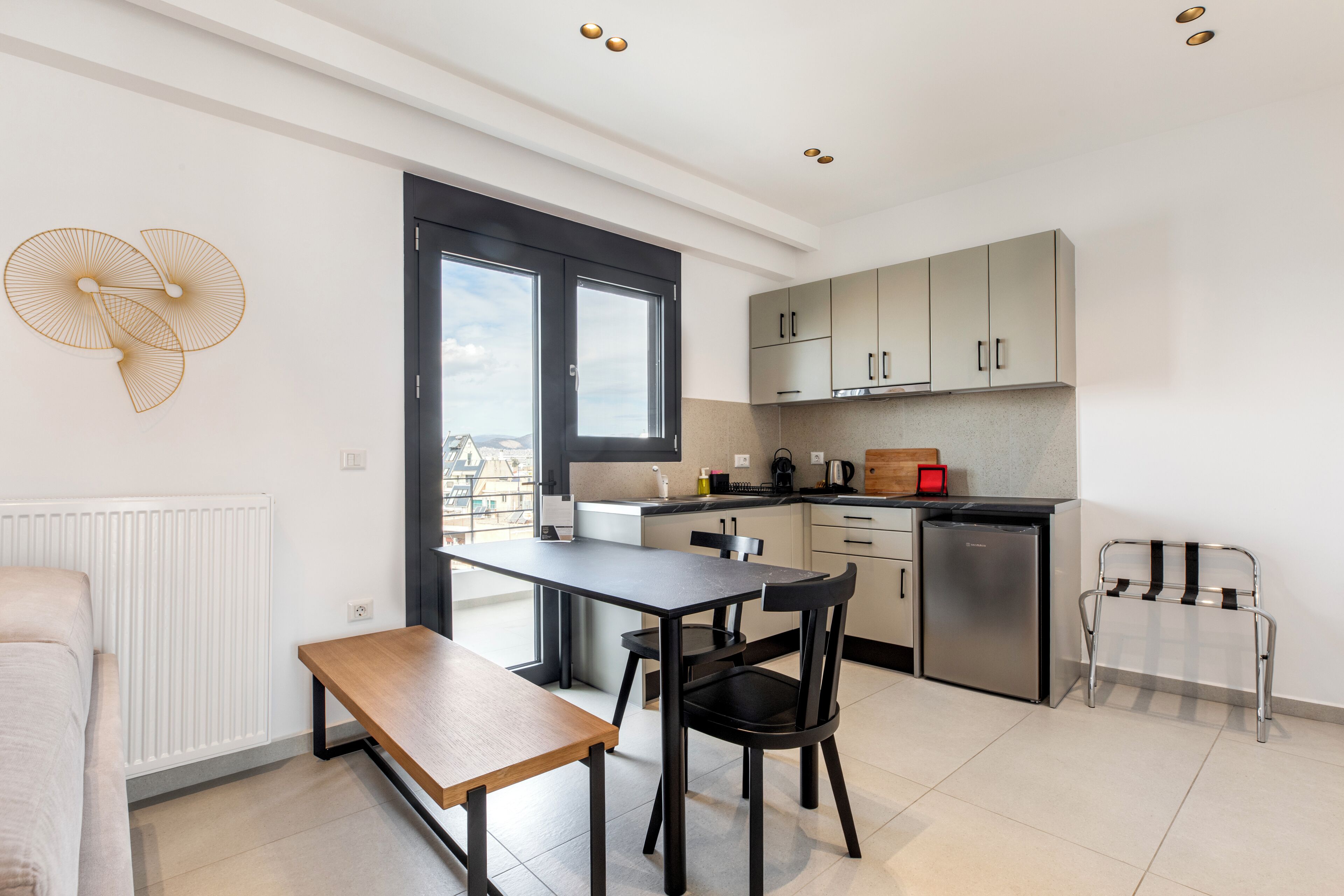 A modern kitchen with a dining area, a bench, and a view through the window.
