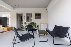 Ein modernes Interieur mit einer Couch, zwei Sesseln, einem kleinen Tisch und einer Topfpflanze.