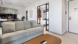 Ein modernes Wohnzimmer mit einer Couch, einem Couchtisch und einer Küche im Hintergrund.