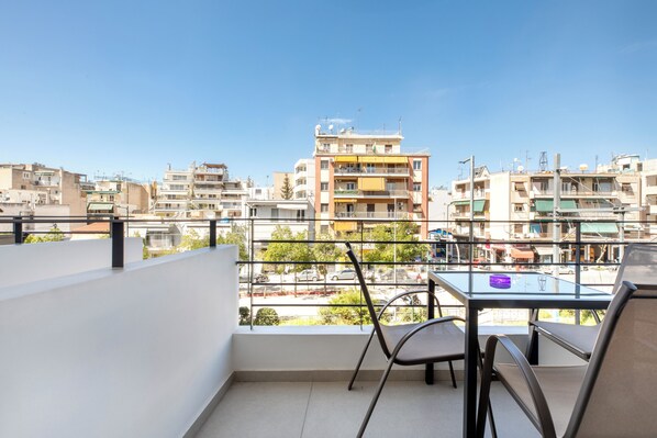 Ein Balkon mit Tisch und Stühlen mit Blick auf eine Stadtlandschaft und mehrere Gebäude.