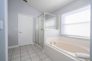 A bathroom with a walk-in shower, a bathtub, and a door.