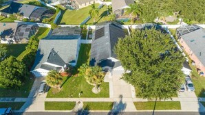 An aerial view of a residential area with houses, a large tree, and a clear sky. - 4 Miles to Disney! Private pool -5 Bedroom Home (Kissimmee)
