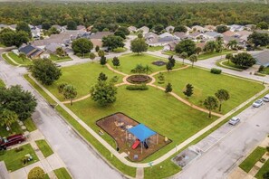 Vista aérea de una zona residencial con casas, un parque infantil y una entrada circular.