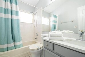 A bathroom with a bathtub, toilet, and a mirror above the sink.