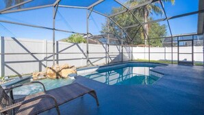 A swimming pool with a hot tub, surrounded by a covered area with a metal frame and glass walls. - 4 Miles to Disney! Private pool -5 Bedroom Home (Kissimmee)