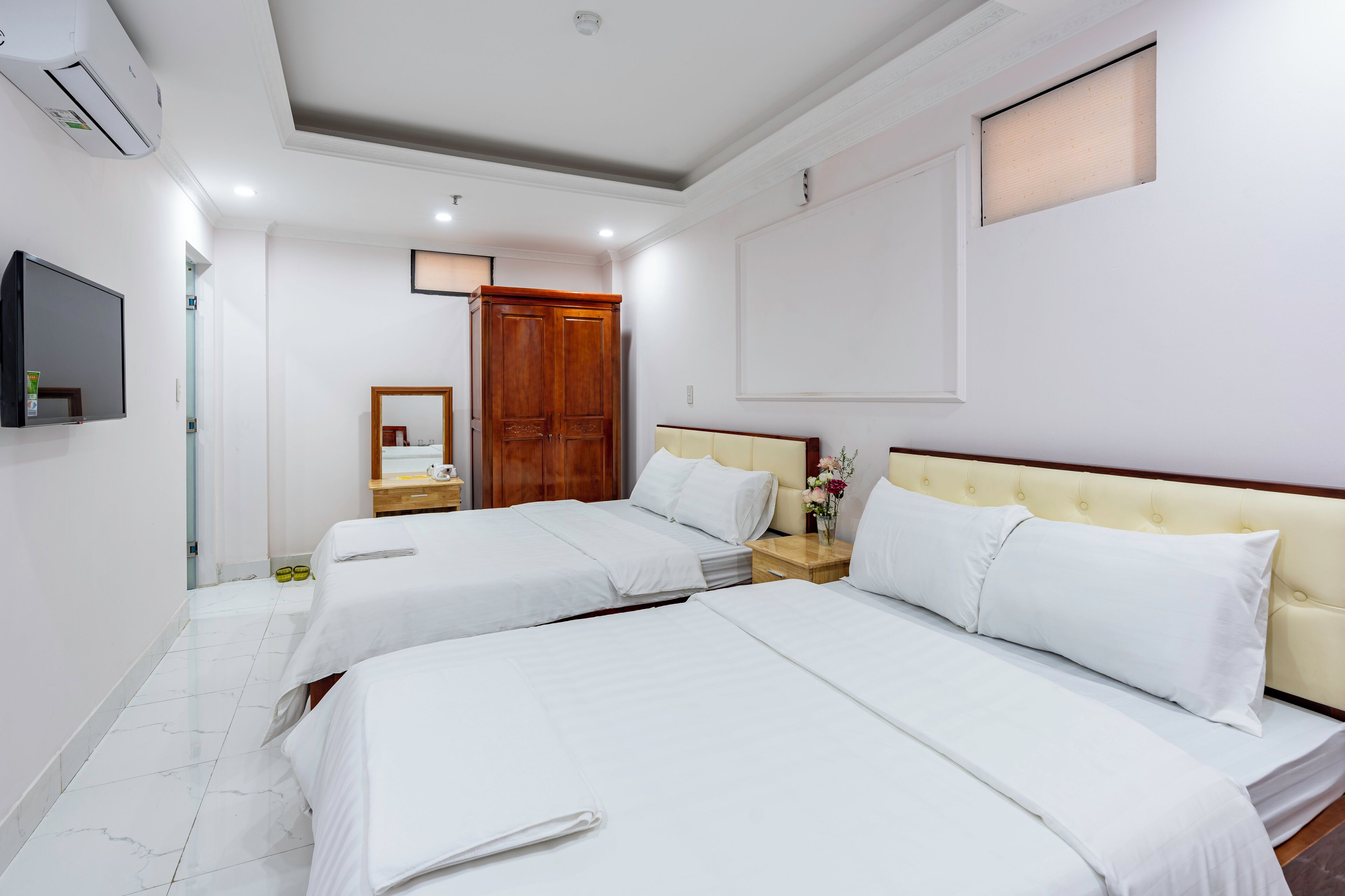 Camera d'albergo con due letti, televisione, specchio, armadio e finestra.