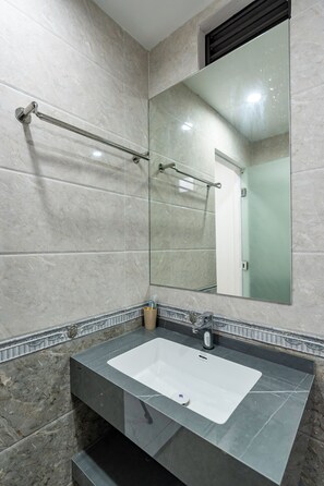 Bathroom features a large mirror above a sink, a towel rack, and tiled walls.