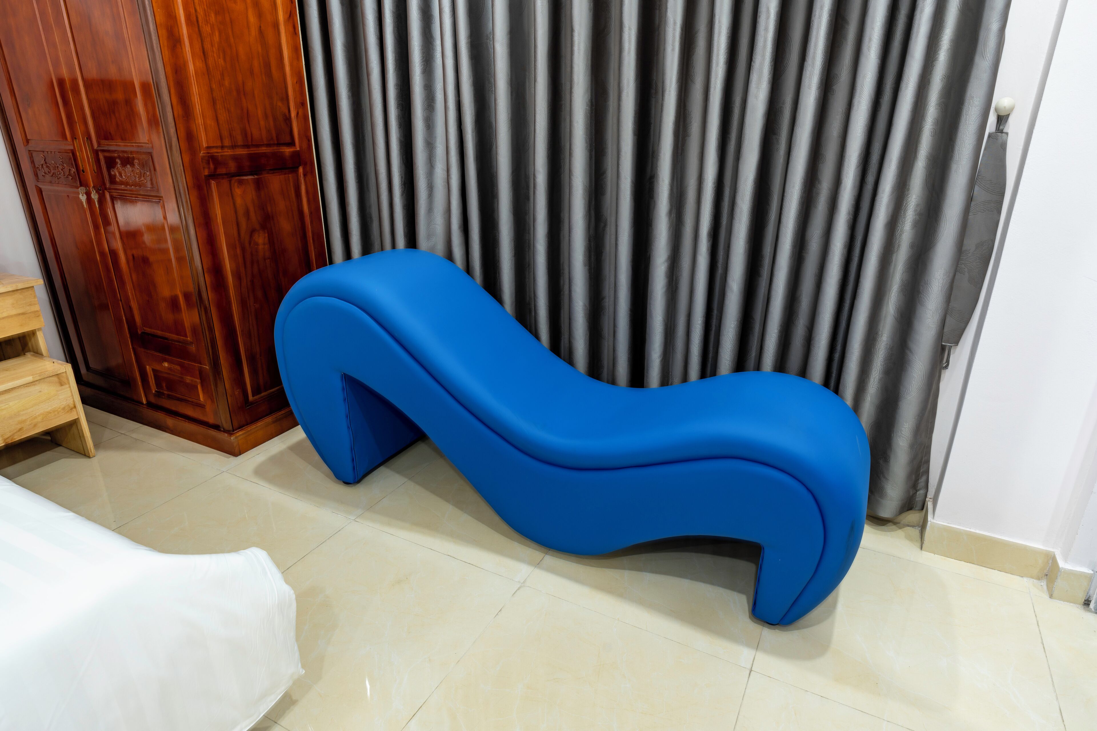 Una habitación con un sofá azul, un armario de madera y una cortina.