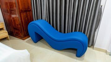 A room with a blue sofa, a wooden wardrobe, and a curtain.