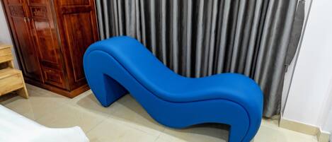 Una habitación con un sofá azul, un armario de madera y una cortina.