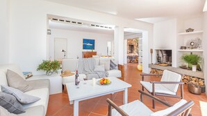 A modern living room with a white sofa, a dining table with fruit, and a fireplace.