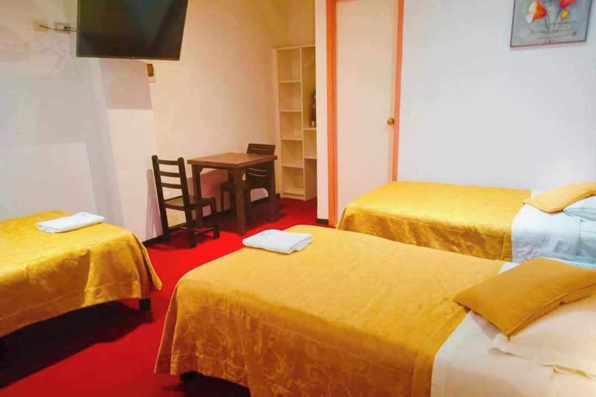 Una habitación de hotel con dos camas, un escritorio, una silla y un televisor.