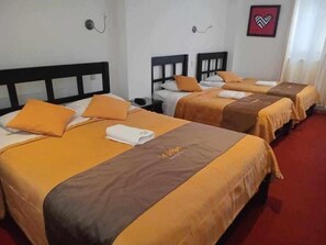 A hotel room with three beds, each with a brown and yellow bedspread, white pillows, and a white towel. - Hotel Le Prince (Tacna)