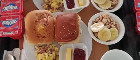 Uma bandeja com itens de café da manhã, incluindo panquecas, ovos mexidos e um muffin, juntamente com acompanhamentos e uma caneca.