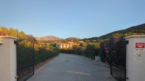 Un camino de entrada cerrado conduce a un edificio con montañas al fondo.
