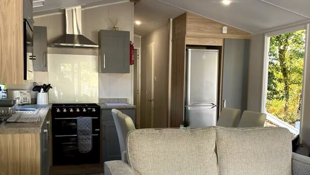 A compact living space with a kitchenette, a sofa, and a window providing a view of the outdoors.