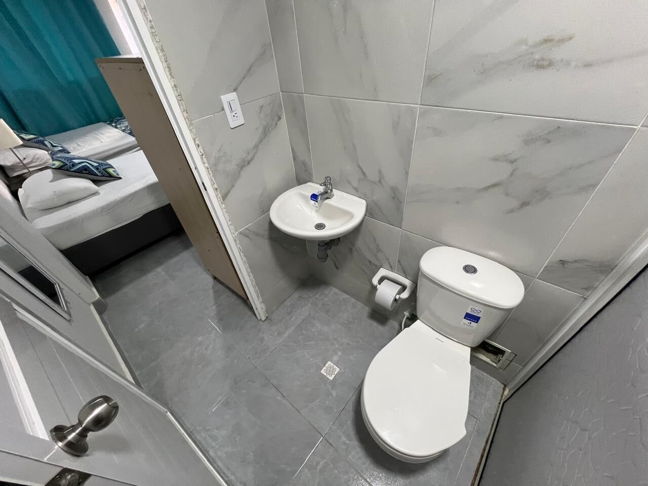 A small bathroom with a toilet, sink, and shower area.