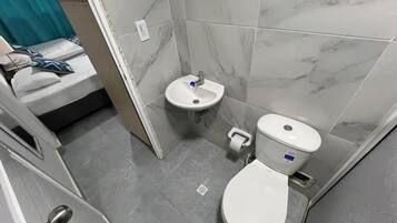 A small bathroom with a toilet, sink, and shower area.