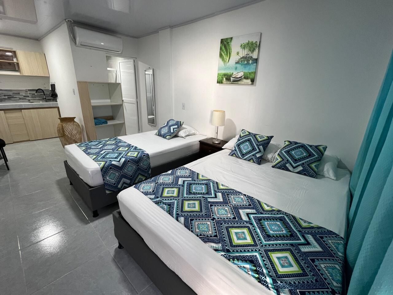 Una habitación de hotel con dos camas, kitchenette y baño.