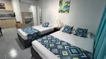 Una habitación de hotel con dos camas, kitchenette y baño.