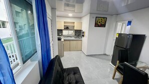 Un espacio habitable compacto con kitchenette, comedor y zona de estar junto a una ventana.