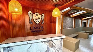 Zona de recepción con mostrador de mármol, paneles de madera y el logotipo de 'LIMSOSOR TOWN BEACH'.