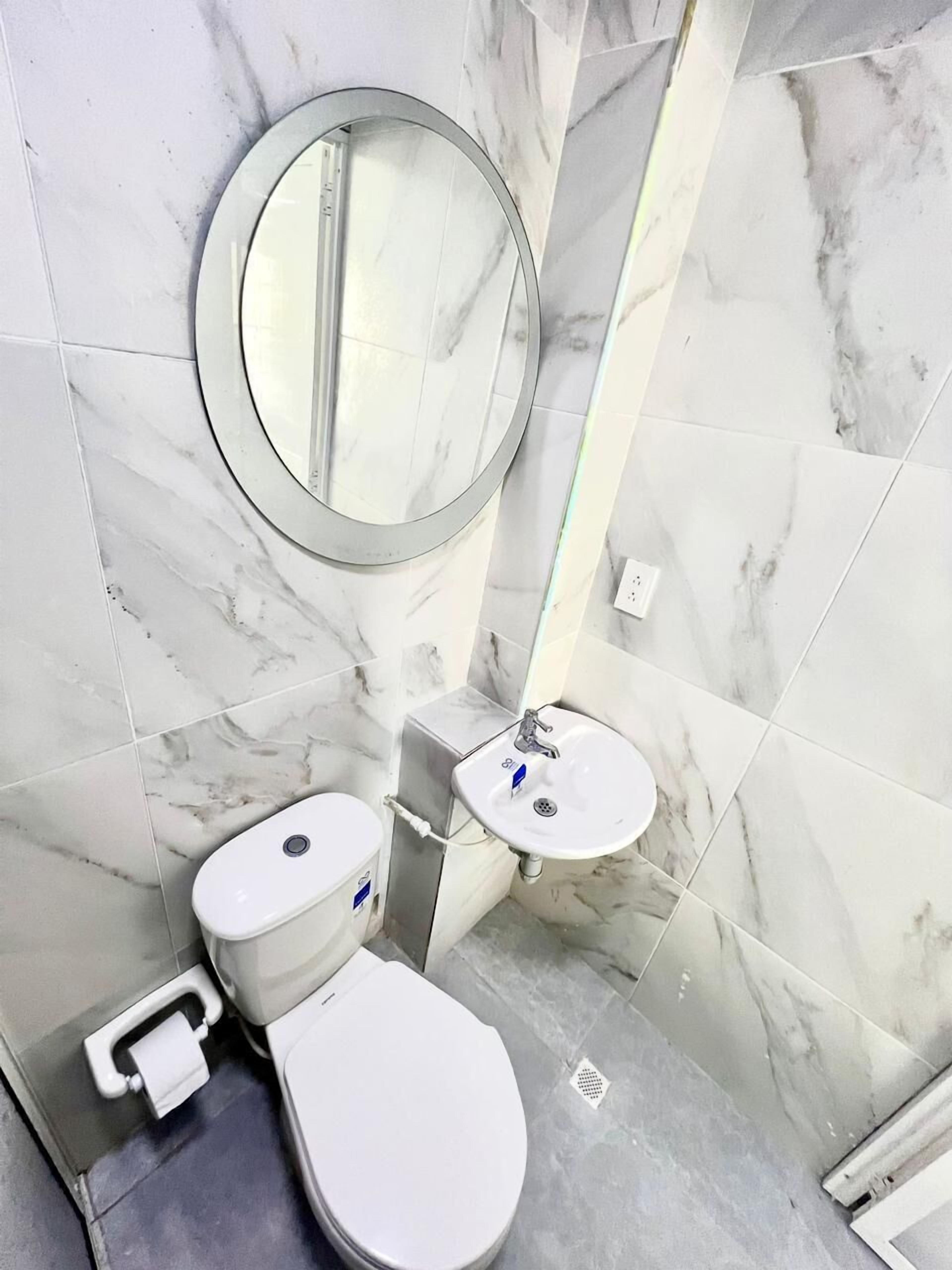 A bathroom with a toilet, sink, and mirror.