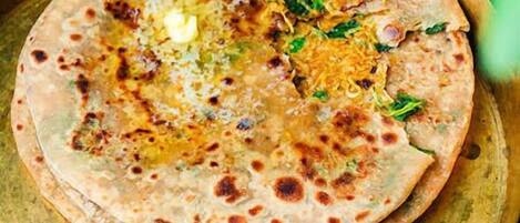 A traditional meal with flatbreads, a bowl of mixed vegetables, and a whole green chili.