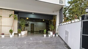 A modern building entrance with a glass door, potted plants, and a tiled floor. - Luxe 8 Stayz  (Gurugram)