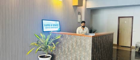 A reception desk with a sign for LUXE 8 STAYZ SERVICE APARTMENTS.
